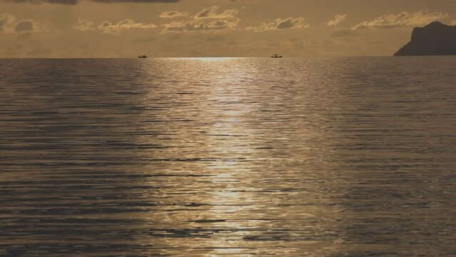 Sunset light and island with water filmed in slow motion at Koh Samu island in Thailand - horizon with two boats in the distance