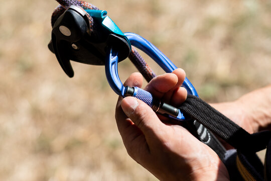 Close Up Shot Of A Man's Hands Operating A Rock Climbing Assisted Belaying Device