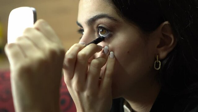 Young woman applying makeup alone. Young brunette girl doing her eye make up