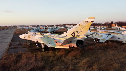 Aerial drone view flight over parking many of old dismantled aircraft. Cemetery of broken crashed planes aircraft at sunset dawn. Close-up top view abandoned aeroplane, old military plane fighter