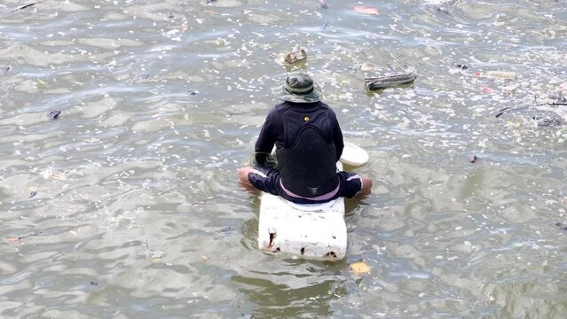 A man sitting on polystyrene floating on the water surface