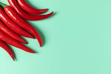 Gardinen Chilischoten Rote scharfe Chilischoten auf blauem Hintergrund.  © Serhii