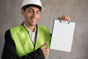 Engineer in a hard hat with a blank clip board in his hands, a place for advertising text
