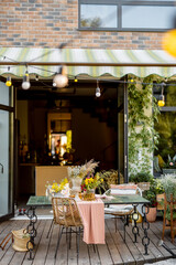 Beautifully decorated dining table with flowers on wooden terrace of country house