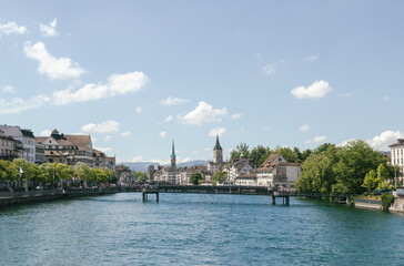 Panorama of Zürich, Switzerland and one of its many bridges over the main city river, with typical old historic buildings all around on a blue sky sunny summer day