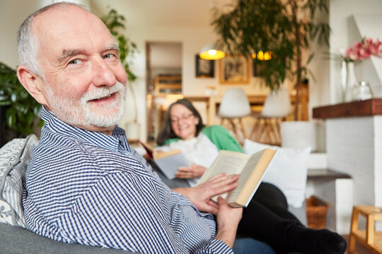 Zufriedener Senior im Wohnzimmer beim Buch lesen