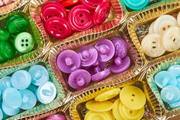 Close-up of a box with a set of multi-colored buttons in plastic cells