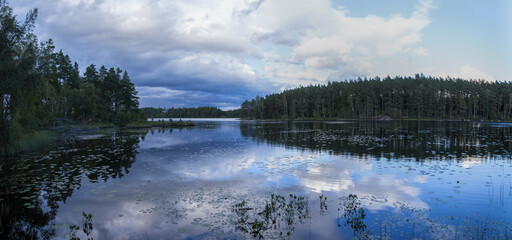 Panorama of a Swedish lake in an atmospherical morning with dramatic clouds