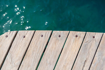 Wooden planks on the pier above the blue sea. Wooden planks on top of the water.