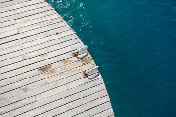 Wooden planks on the pier above the blue sea. Wooden planks on top of the water.