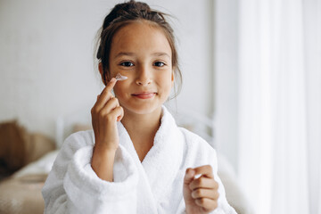 Cute girl applying face cream