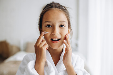 Cute girl applying face cream - Powered by Adobe