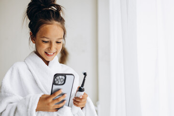 Cute girl brushing teeth and using phone - Powered by Adobe