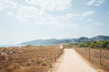 Fototapeta na wymiar Un sentier côtier entre les dunes de sable sur la Costa Brava. Un petit chemin de bord de mer. Un chemin de randonnée au bord de la mer