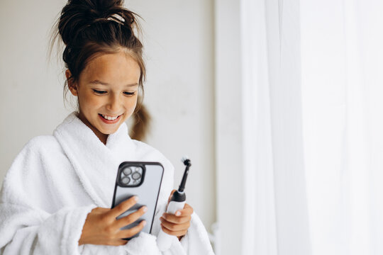 Cute Girl Brushing Teeth And Using Phone