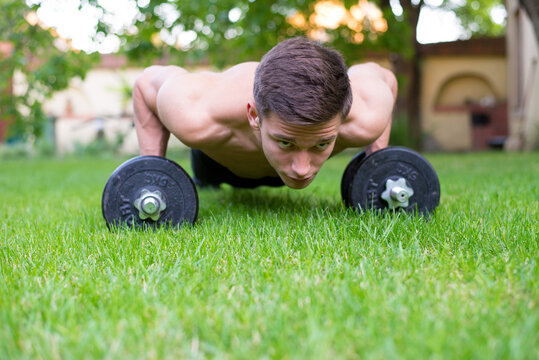 Young strong man doing pushups on the backyard grass in summer