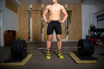 Young strong man lifting heavy weights in sports gym