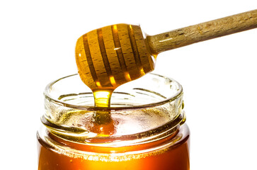 Getting honey from a jar with a honey spoon isolated on white background