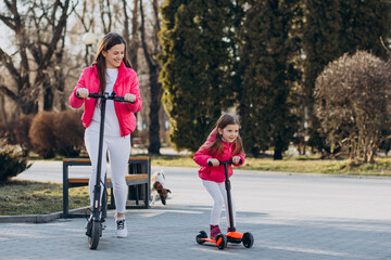 Mother with daughter riding electric scooter