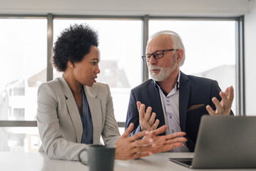 Business coworkers brainstorming while working on laptop during the meeting.