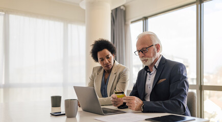 Professionals doing online transaction through credit card on laptop at the office.