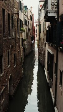 A narrow space between old traditional houses above one of the Venice canals