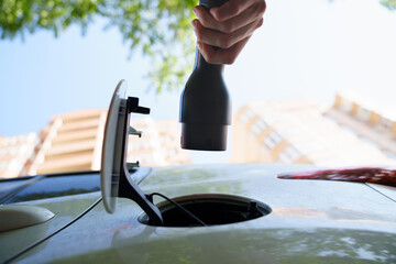 hand of woman plugging in an electric car at outlet socket.