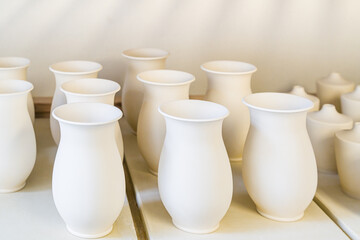 A group of porcelain  high flowerpots dry on pallets before glazing and firing.