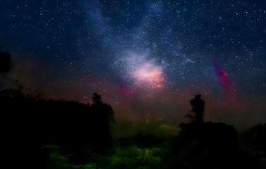Naklejka na ściany i meble Milky Way and pink light at mountains. Night colorful landscape. Starry sky with hills at summer. Beautiful Universe. Space background with galaxy. Travel background