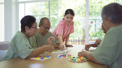 Portrait of happy group of old elderly Asian patient or pensioner people with a nurse playing games...