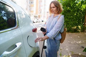 woman plugging in an electric car at outlet socket.