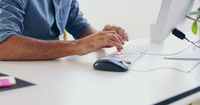 Hands of a business man typing on a keyboard, sending an email or updating a work document online. Closeup of a professional male working at his desk in the office. Clicking a mouse and scrolling