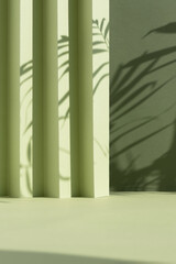 Abstract green background with shadow of palm leaves for the presentation of a cosmetic product. A scene with a geometric backdrop. Podium for product promotion, beauty, natural eco cosmetic. Showcase