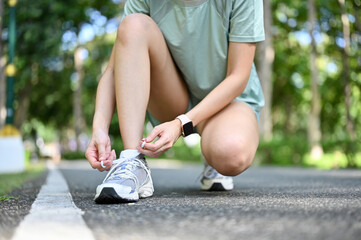 A healthy and active young female in sportswear tying running shoelaces. cropped image - obrazy, fototapety, plakaty