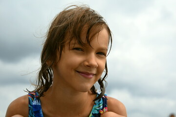kid 7 years old  smile eyes closed-up head and shoulders only sky summer beach happy pleasure after swimming from the ground wet hair tan