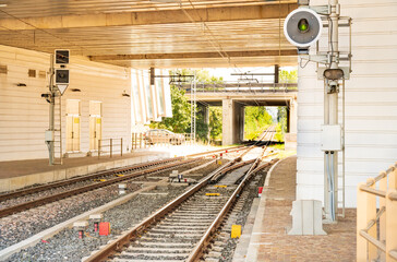Rails of the railway track come out of the tunnel under the overpass and go into the distance among...