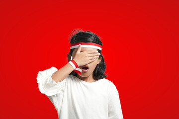 isolated girl using red and white ribbon closes eyes with hands and is surprised.
