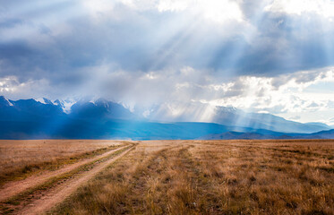 country road in the sun against the backdrop of a mountain landscape
