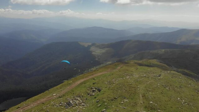 Following paraglider flying above carpathian mountains. Drone footage 4K. Ukraine.