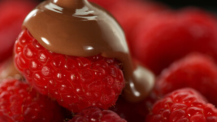 Freeze motion of pouring melted chocolate on raspberries.