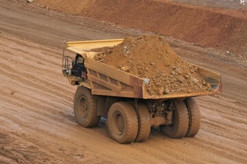 A haul truck is transporting material at a nickel mine site. Rigid dump trucks specifically engineered for use in high-production mining and heavy-duty construction environments.