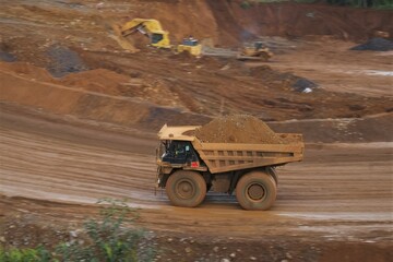 A haul truck is transporting material at a nickel mine site. Rigid dump trucks specifically engineered for use in high-production mining and heavy-duty construction environments.