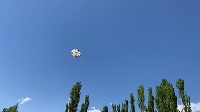 A boat pulls a parachute across the sea with two tourists flying over the shore. Entertainment and active recreation of people at the sea in summer.