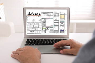 Designer creating website on laptop at white table, closeup