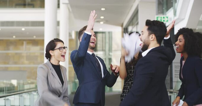 Business team throwing paper in the air, carefree, happy and excited. Colleagues cheering and celebrating the end of the working week. Team members overjoyed at successful results