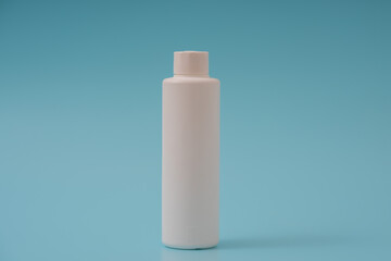 White plastic bottle with a green cap on a blue background