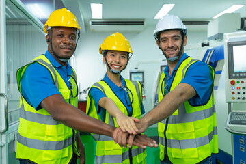 Group of young multiethnic confident male and female Engineers and Worker in safety uniform and helmet join hand together in factory. Successful business and teamwork