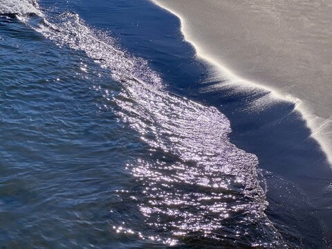 Shiny sea waves on the sandy beach shore.