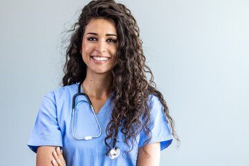 Female nurse looking towards camera, wearing blue scrubs, arms crossed. Medical professional...