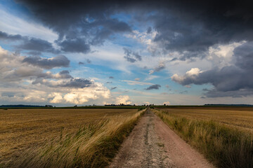 Dramatic storm clouds over fields. Country landscape. Windy weather. Plain field against the background of dark sky.
